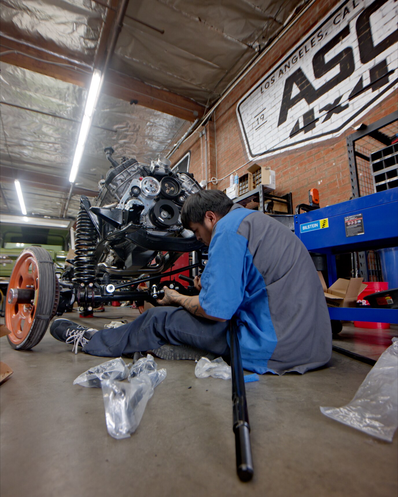 ASC 4x4 technician fitting front suspension to a Bronco chassis in the shop